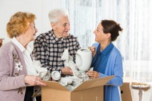 Senior couple and friend unpacking box